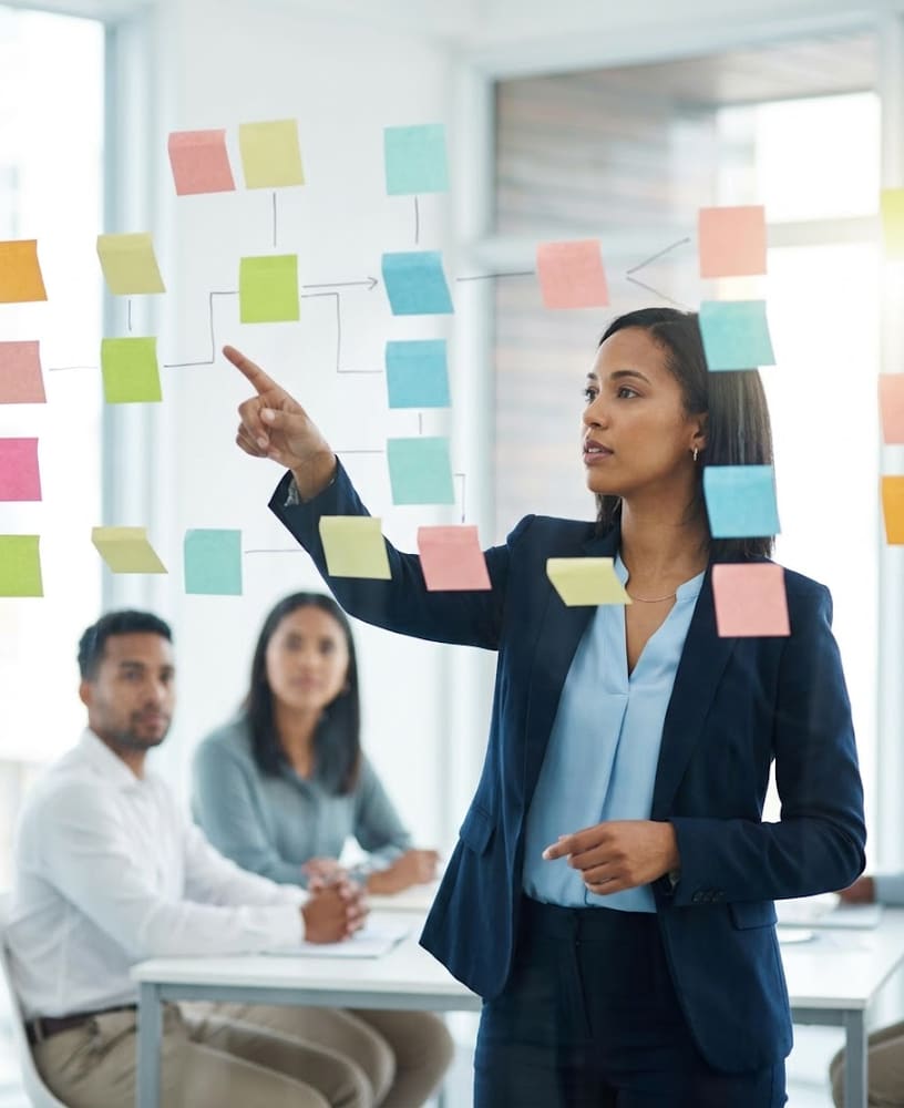 Gestora apontando um fluxograma de processos em post-its